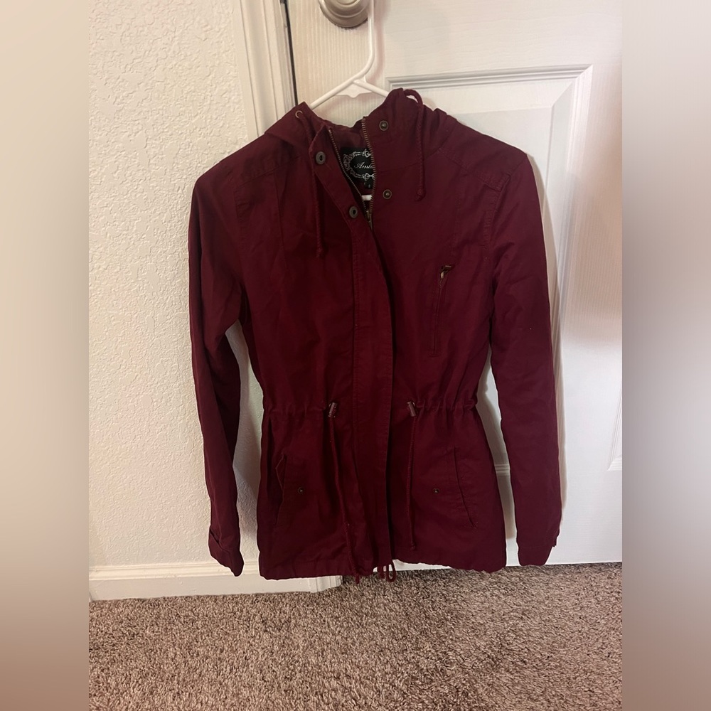 Small maroon zip up coat with hood.